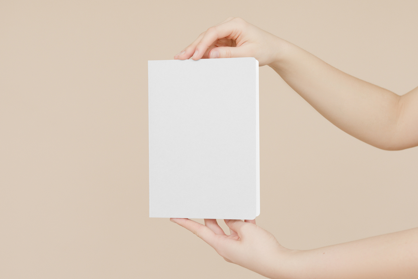 Front view, blank book mockup in man's hand in front of the beige wall.