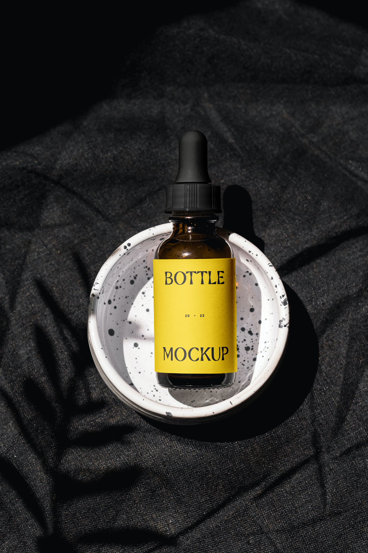 View from above, cosmetic bottle mockup with yellow label laying it's in the terrazzo ashtray.