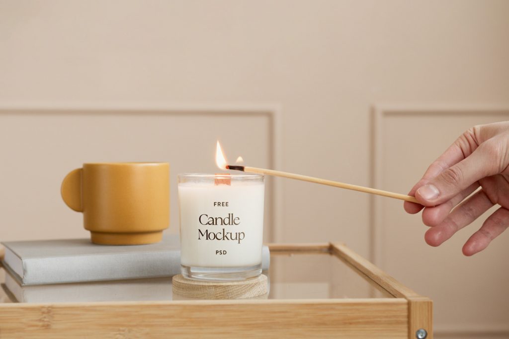 Front view, white lit candle mockup standing on the glass table with wooden frames.