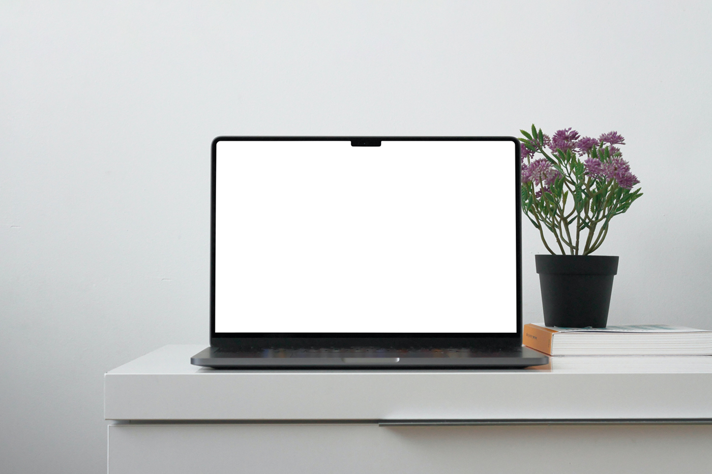 Front view, MacBook Pro Mockup with white screen laying on the white chest of drawers.