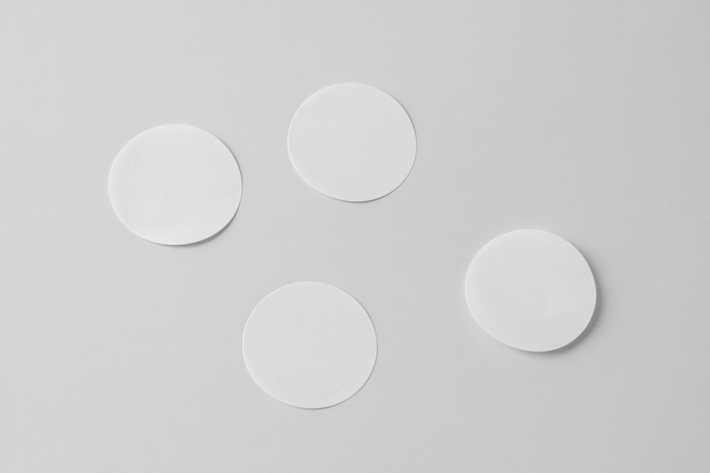 Three rounded white sticker mockup laying on the white floor.