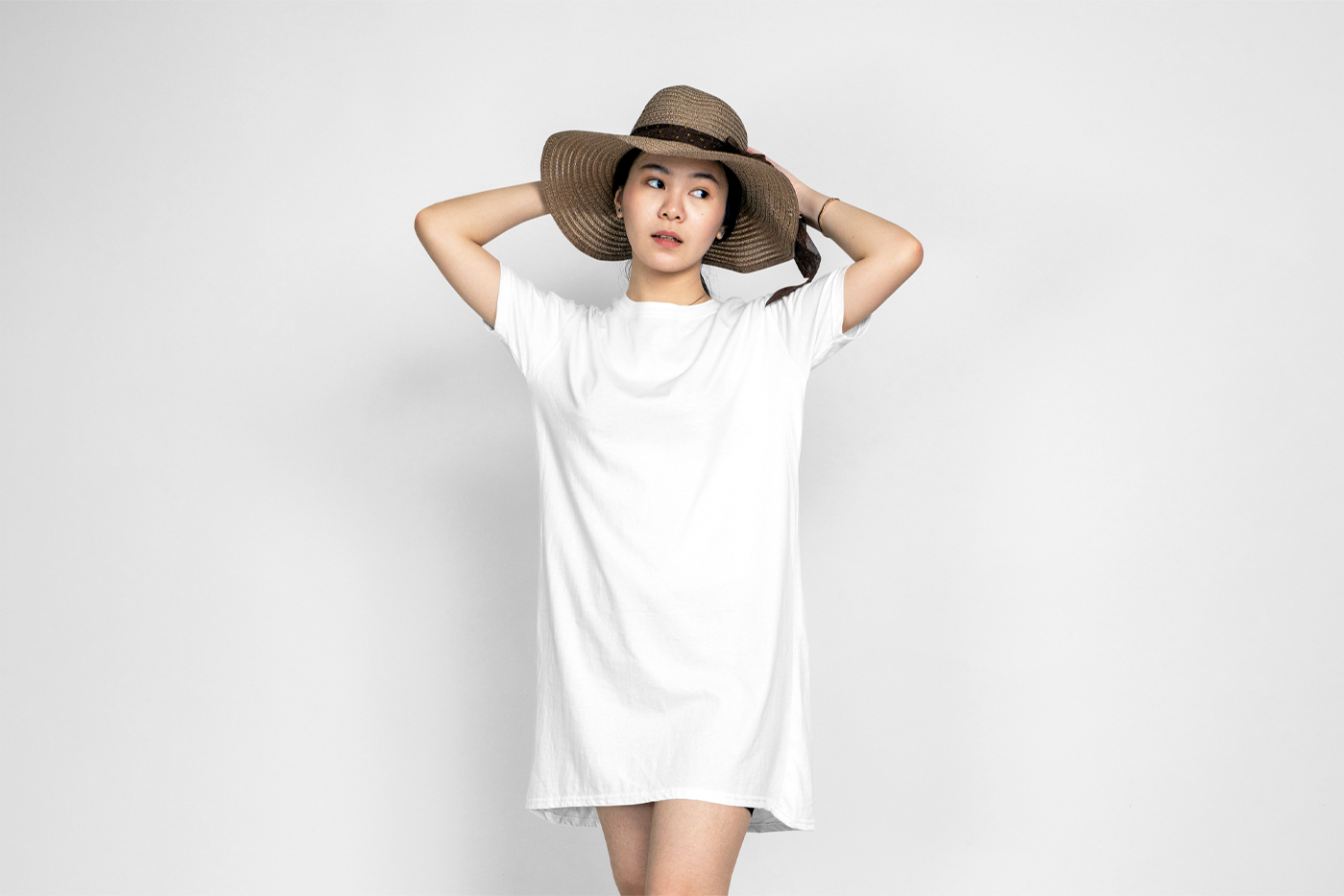 A woman wearing a white tunic mockup in front of the white wall.