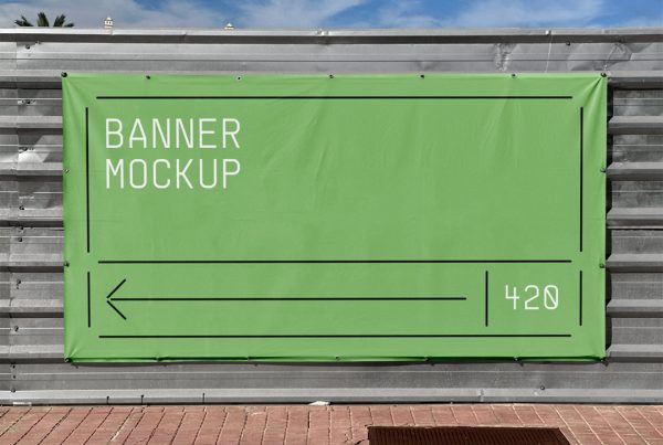 Green banner mockup hanging on the silver construction fence with a visible sky behind.