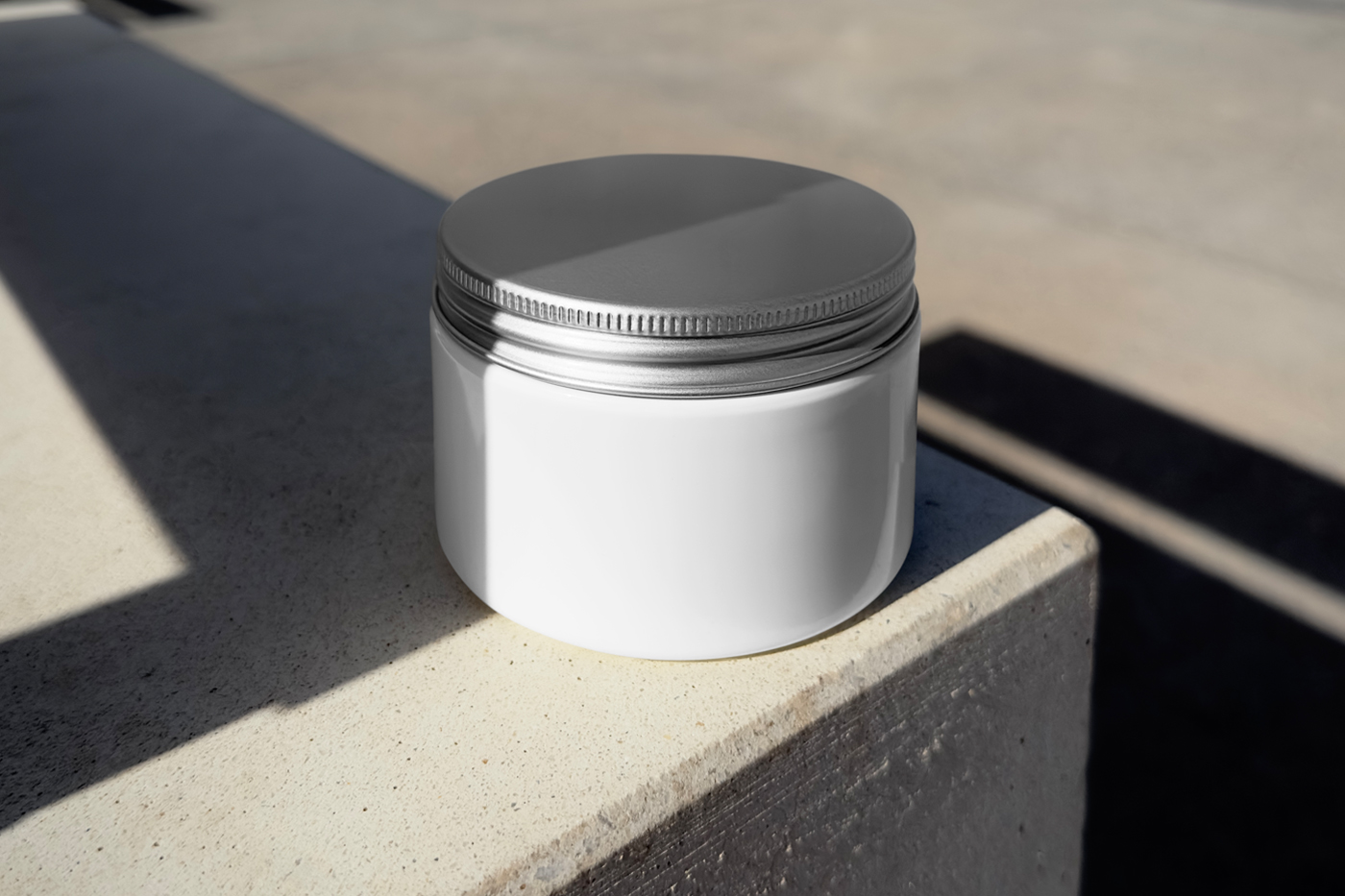 Front view, white jar mockup with silver lid laying on the concrete floor.