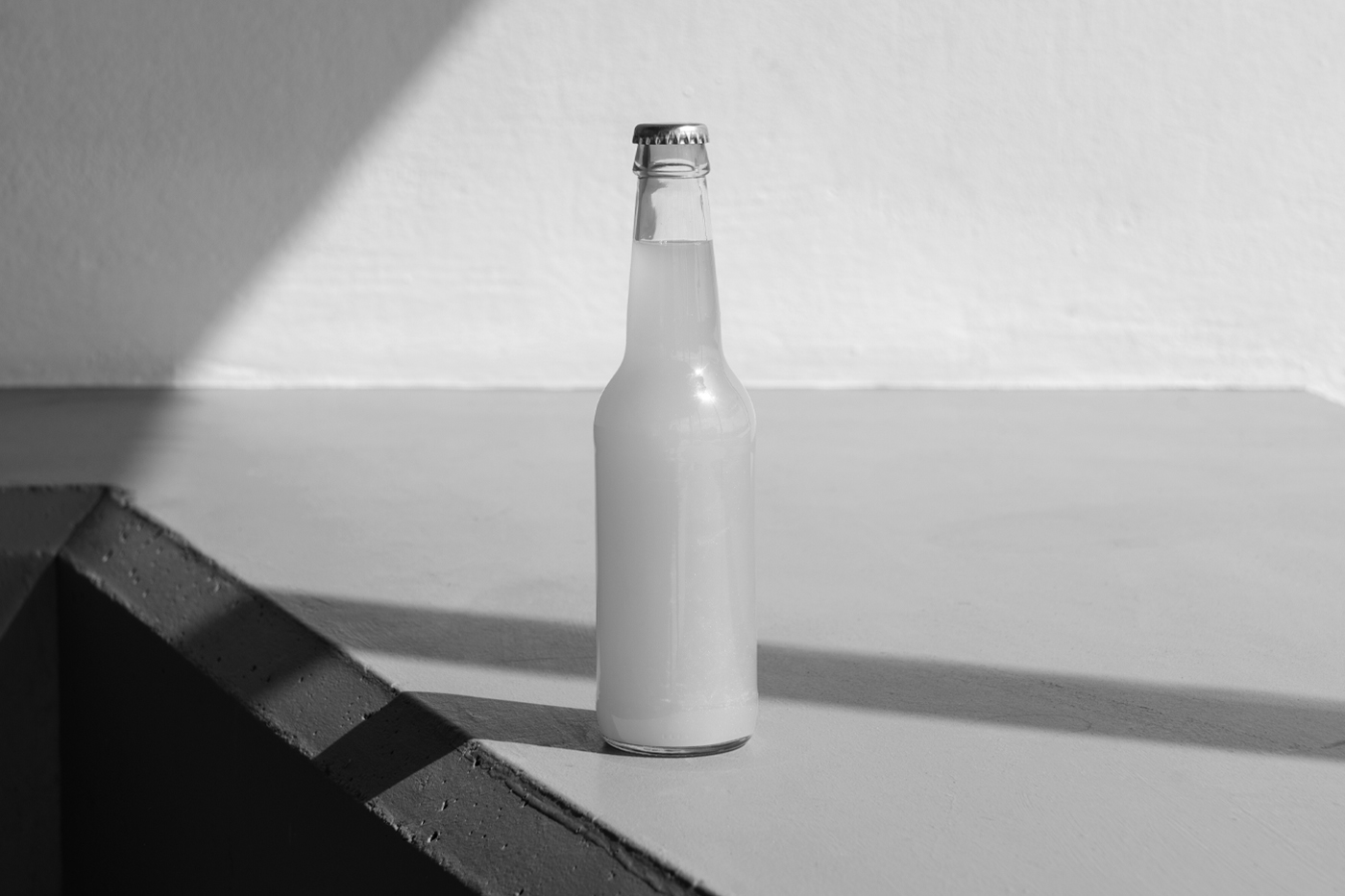 Blank soda bottle mockup standing on the white floor in front of the white wall.