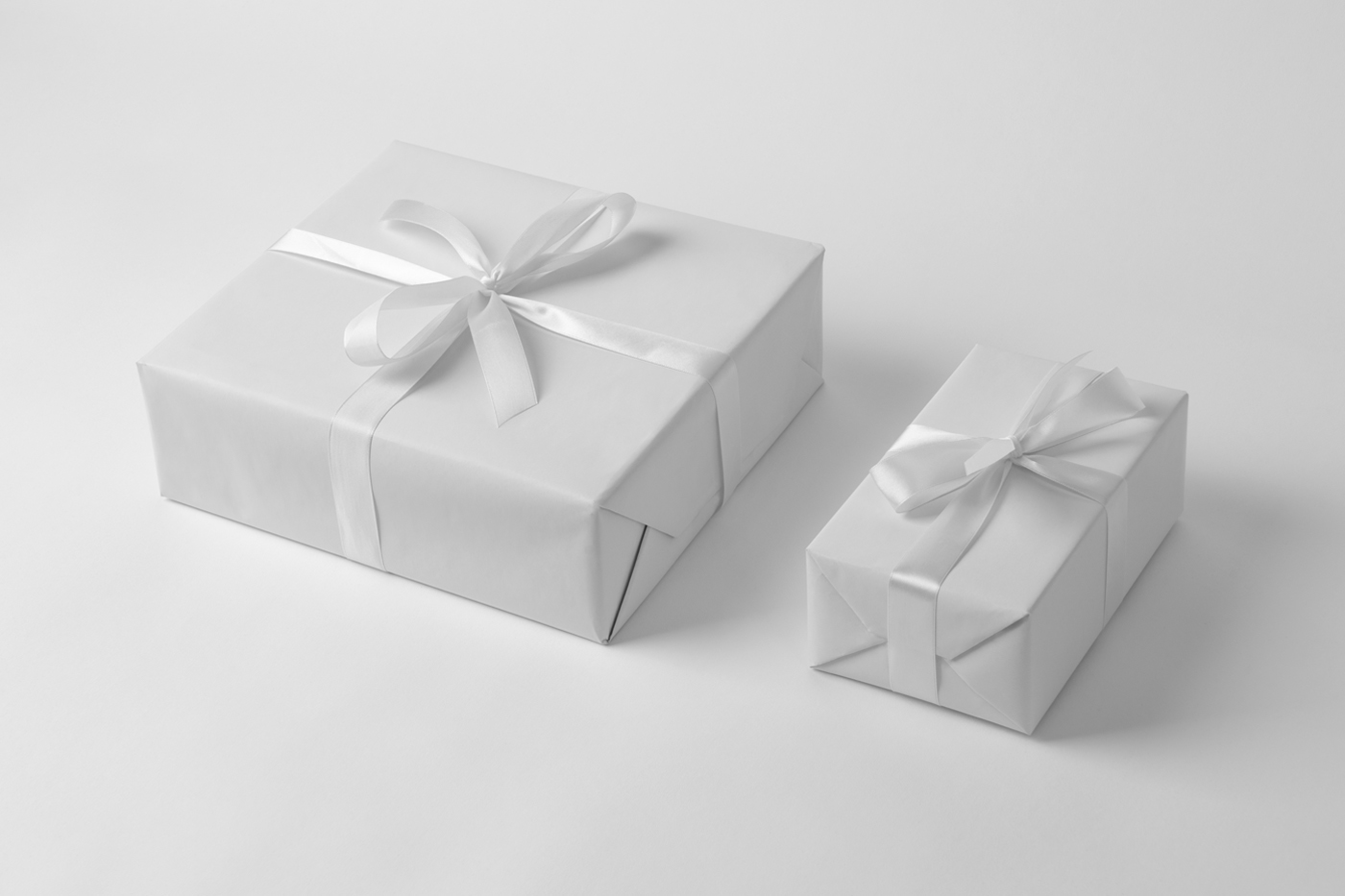 White Valentine's gift boxes mockup with ribbon laying on the white floor.