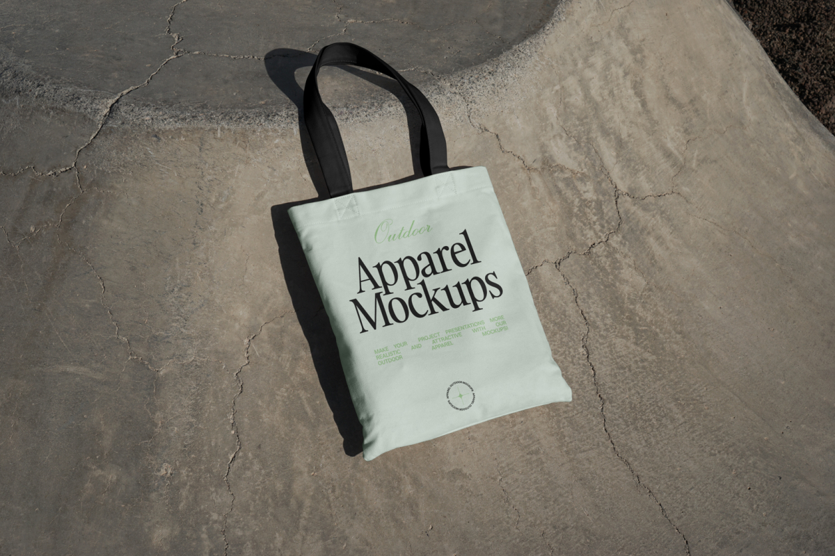 Green canvas bag with black handle laying on concrete ground.