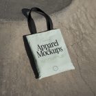 Green canvas bag with black handle laying on concrete ground.