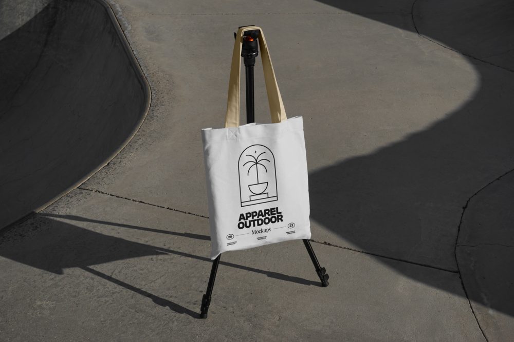 White canvas bag with yellow handle hanging on black tripod.