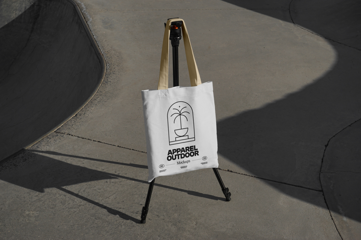 White canvas bag with yellow handle hanging on black tripod.
