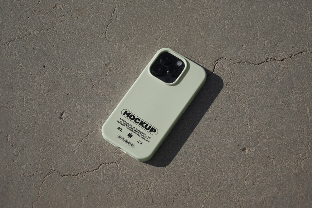 iPhone pro with green case laying on concrete floor.