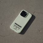 iPhone pro with green case laying on concrete floor.