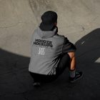 Man wearing dark grey hoodie and black cap on the concrete skatepark.