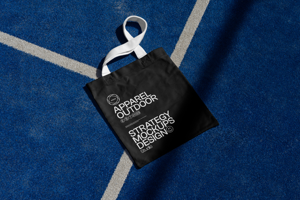Black canvas bag with white handle laying on blue court.