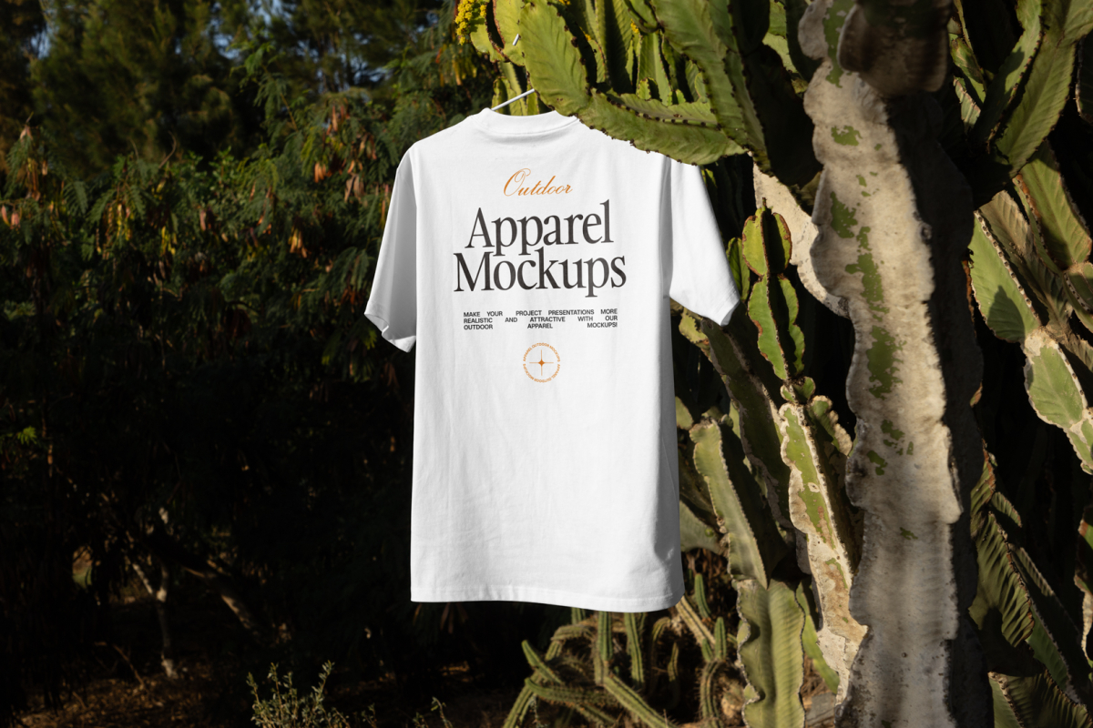 White t-shirt with black and yellow typographic design hanging in front of big cactus.