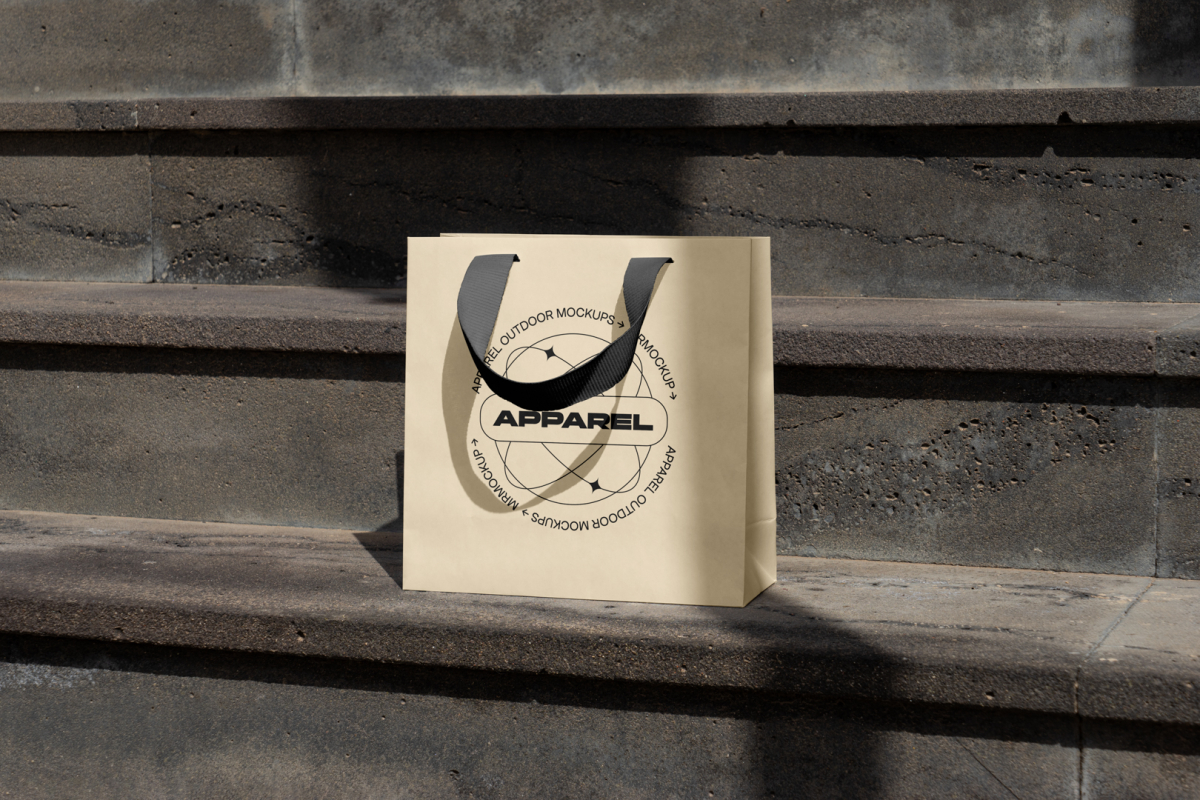 Small yellow paper bag with black handle on the concrete stairs.