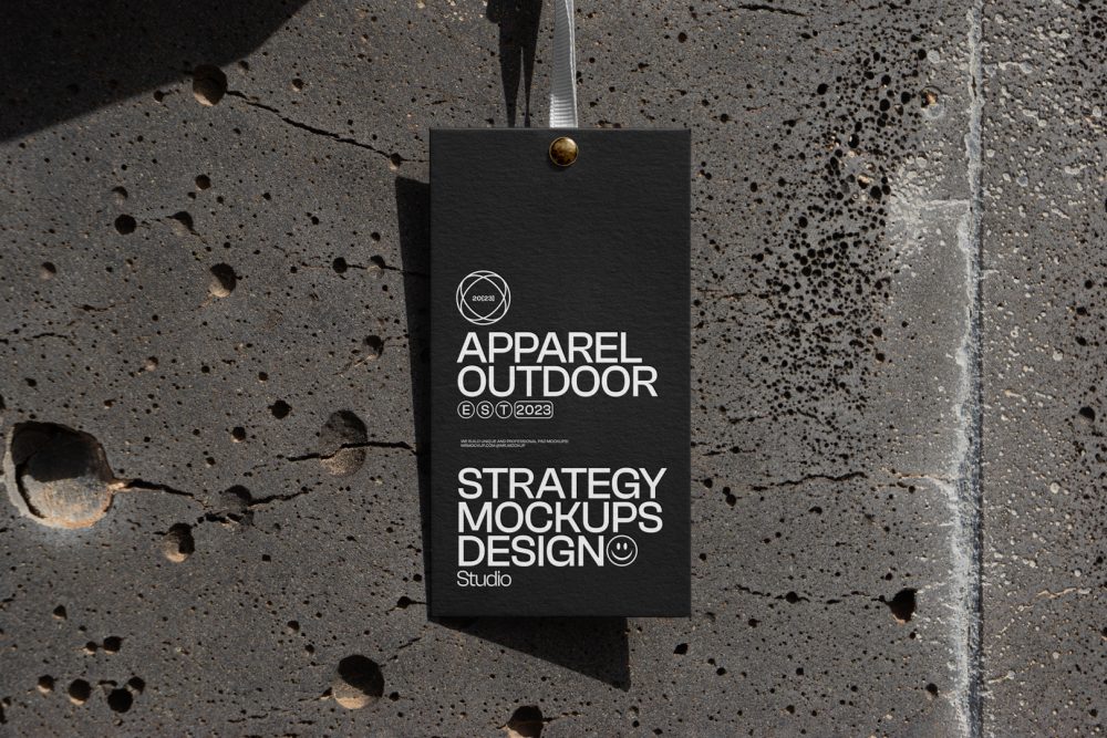 Black paper tag hanging in front of concrete wall.