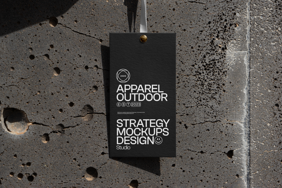 Black paper tag hanging in front of concrete wall.
