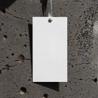 Paper tag hanging in front of concrete wall from outdoor apparel mockups vol.2.