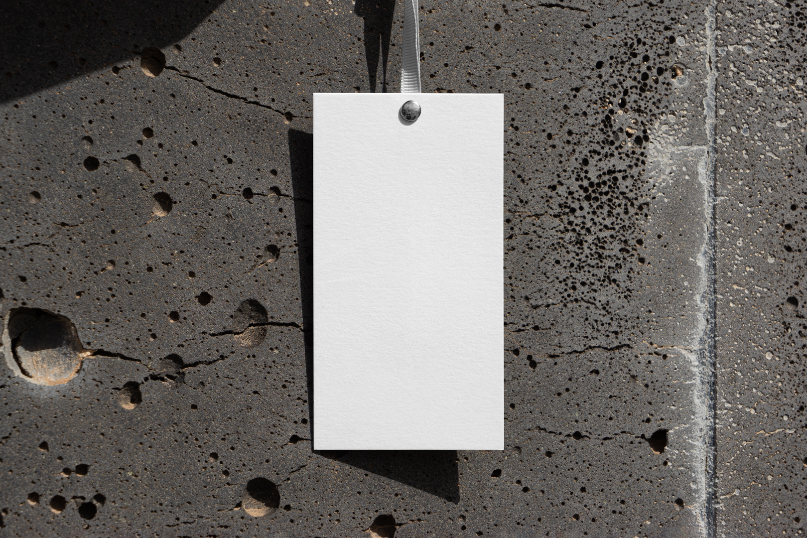 Paper tag hanging in front of concrete wall from outdoor apparel mockups vol.2.