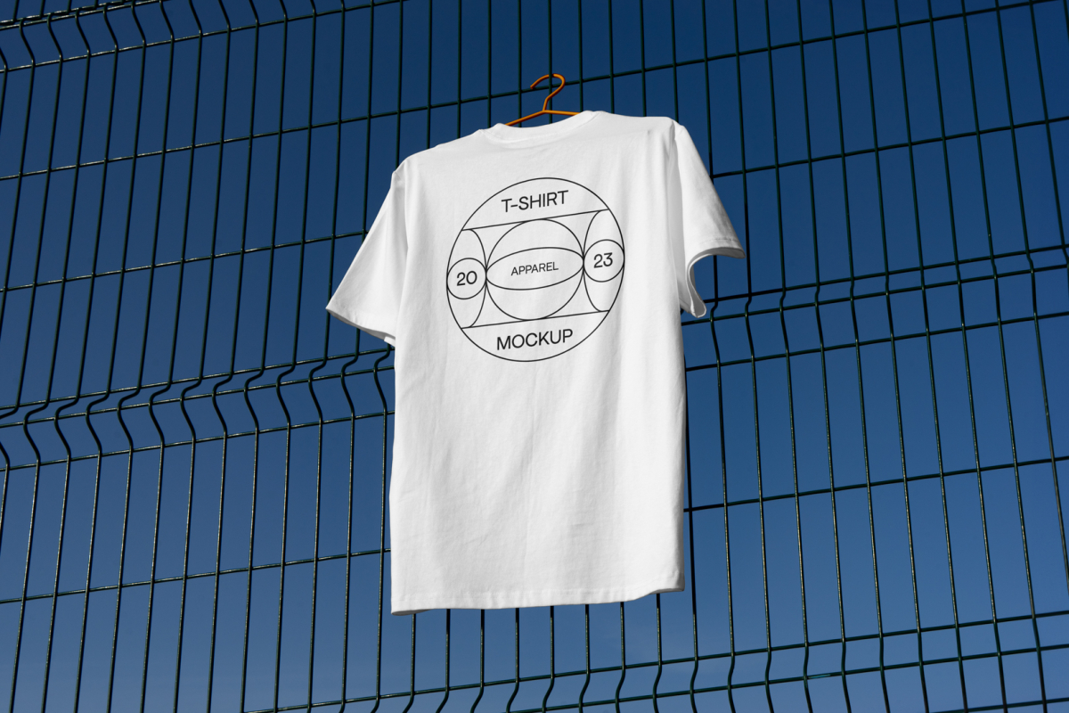 White t-shirt with black typographic design hanging on the metal fence.