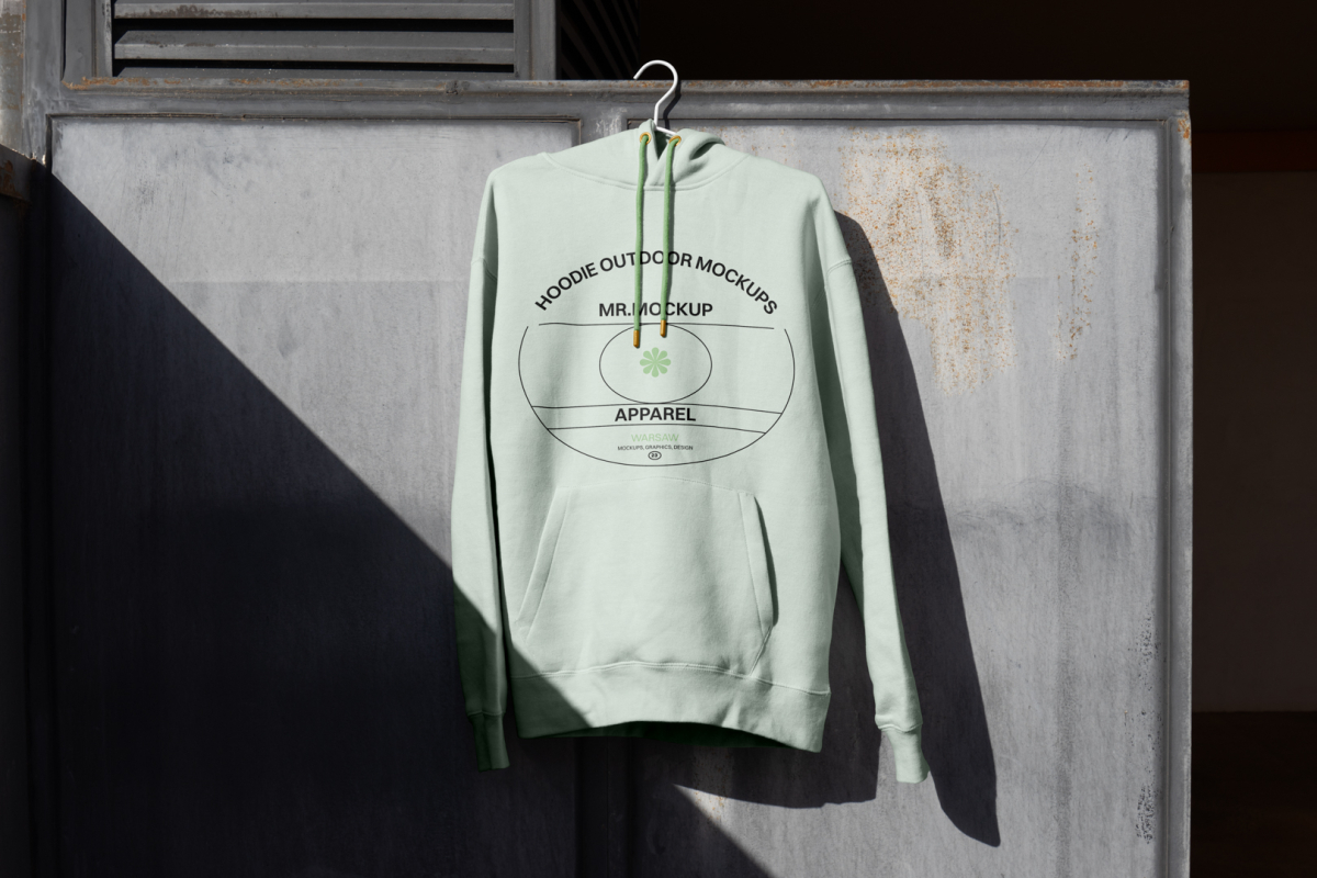 Green hoodie hanging in front of metal wall.