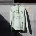 Green hoodie hanging in front of metal wall.