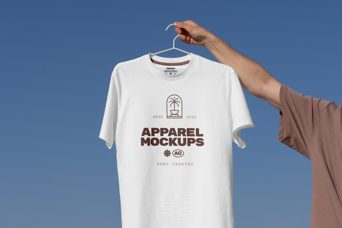 Man holding white t-shirt with brown typographic design.