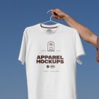 Man holding white t-shirt with brown typographic design.
