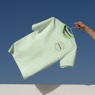 Man holding green t-shirt in front of blue sky.