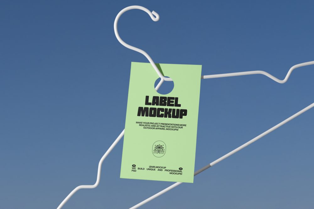 Metal hanger with green paper tag in front of blue sky.