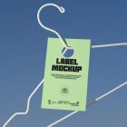 Metal hanger with green paper tag in front of blue sky.