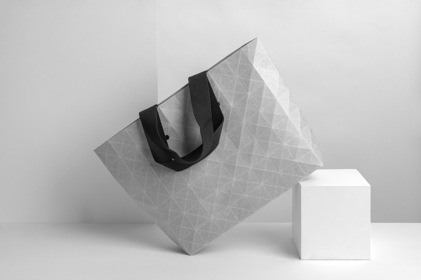 White big paper shopping bag mockup with black handle, based on the white box in front of the white wall.