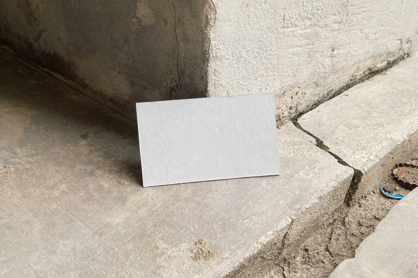Front view, blank business card based on the wall corner and standing on the concrete floor.