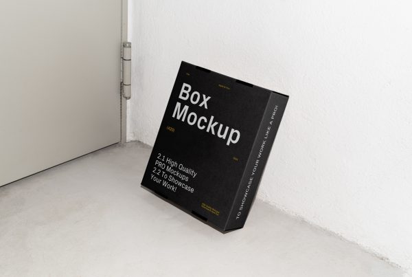 Front view, of a black cardboard box mockup with white strong typography design based on a white wall and standing on the concrete floor.