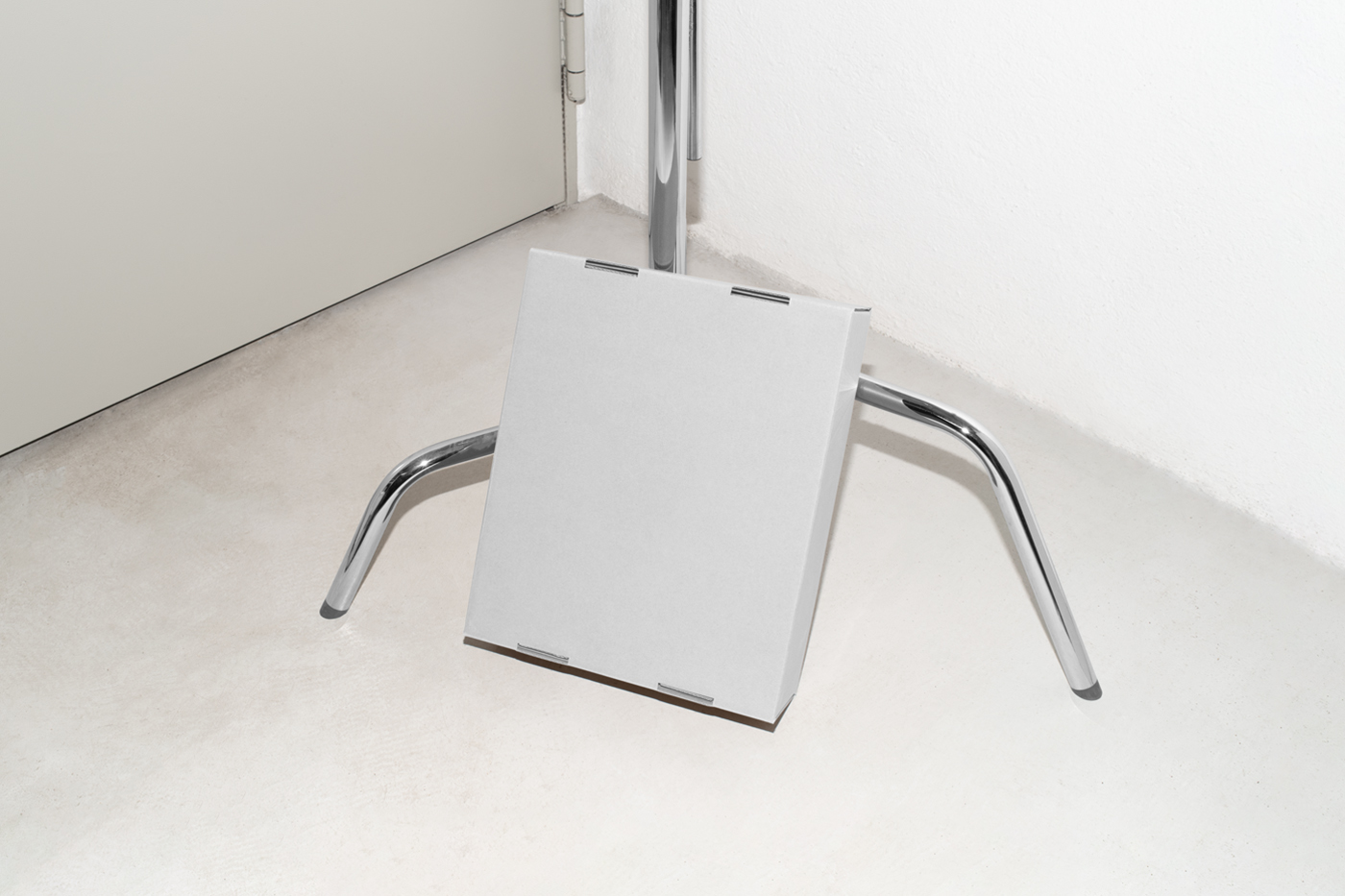 View from above, of a white cardboard box mockup based on a metal tripod.