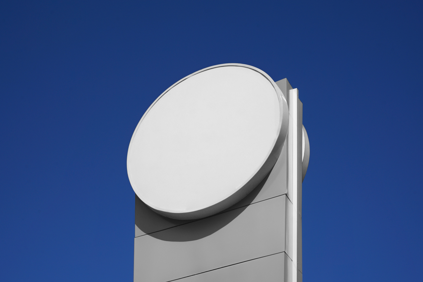 Front view, white circle sign mockup attached to the white construction, with a visible sky behind.