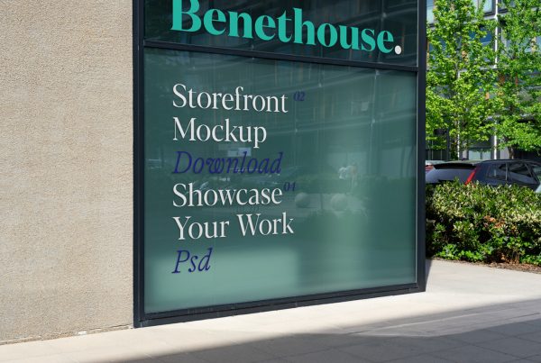 Front view, at an angle of 45 degrees, building corner storefront mockup with white and blue typography design with reflection of city life. Behind the corner are trees, cars, and another building.