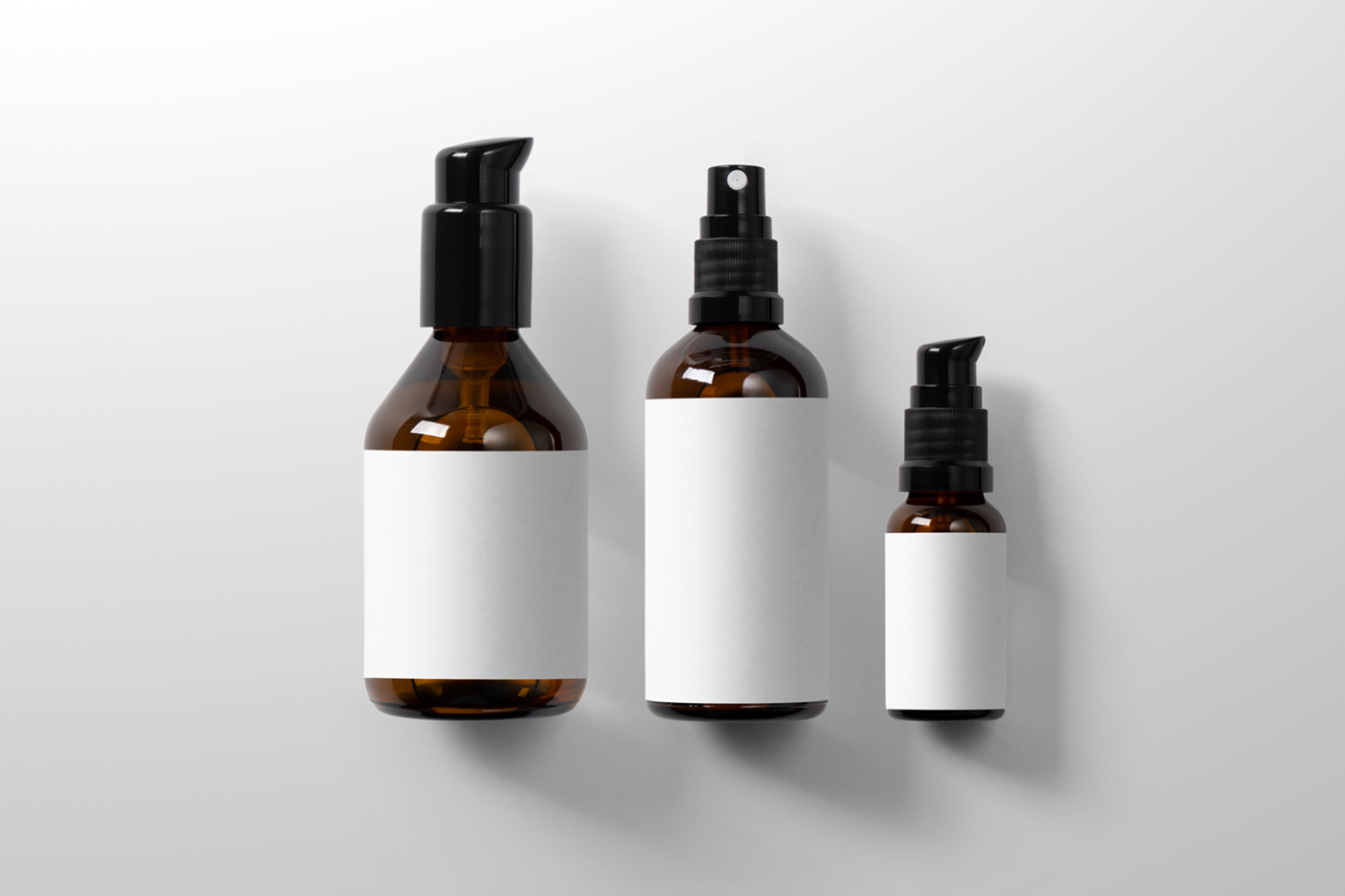 View from above, three cosmetics packaging bottle mockup with white labels laying on the white floor.