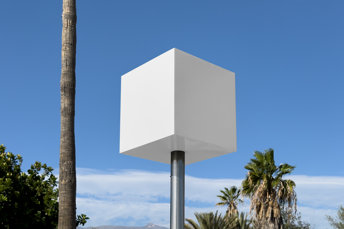 Front view, white square sign mockup standing between trees with a visible sky behind.