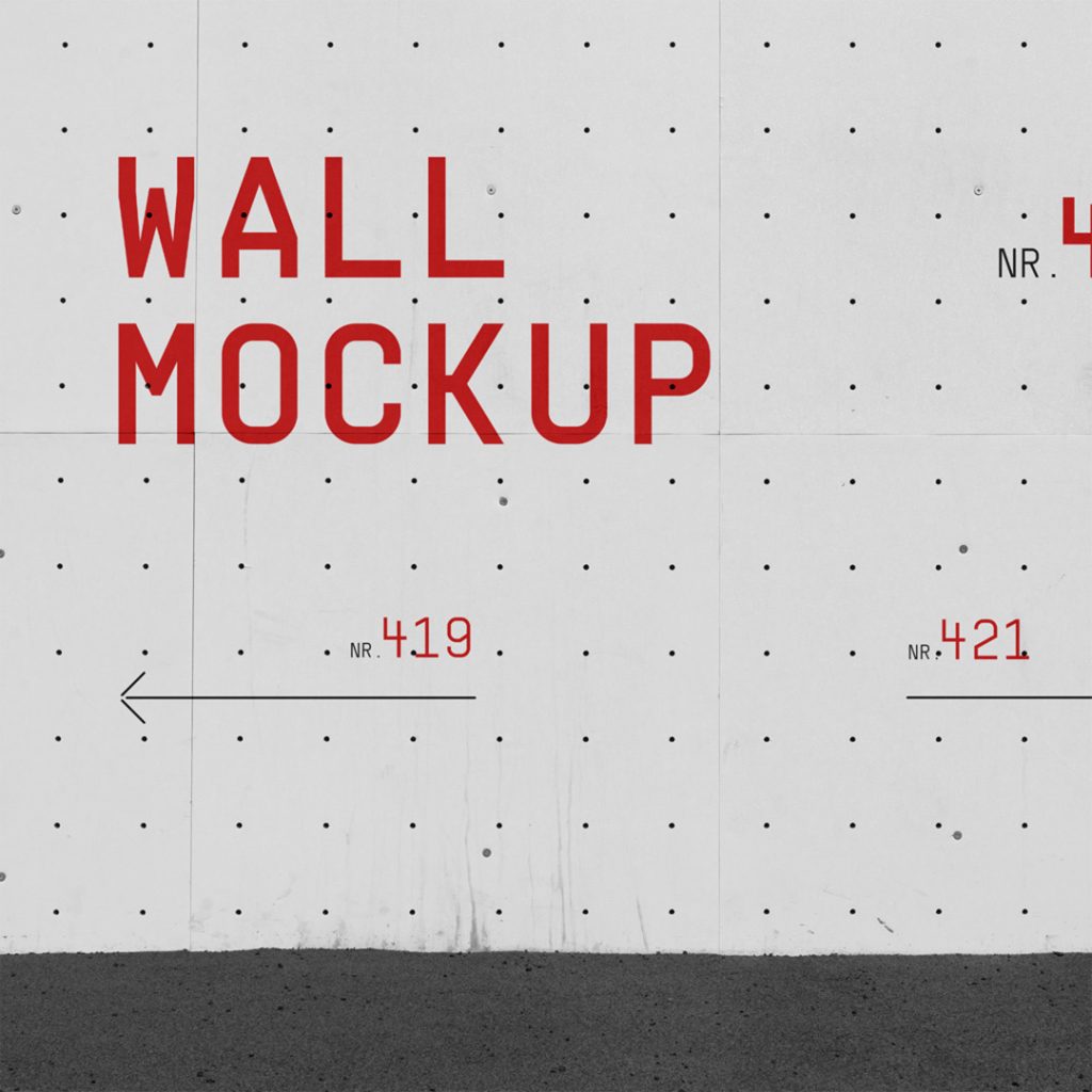 Front view, concrete wall mockup with red typography design against asphalt pavement.