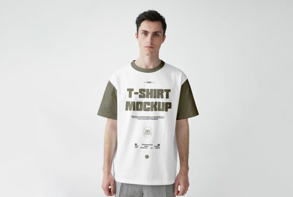 Standing men wearing t-shirt with a green logo in front of the white wall.