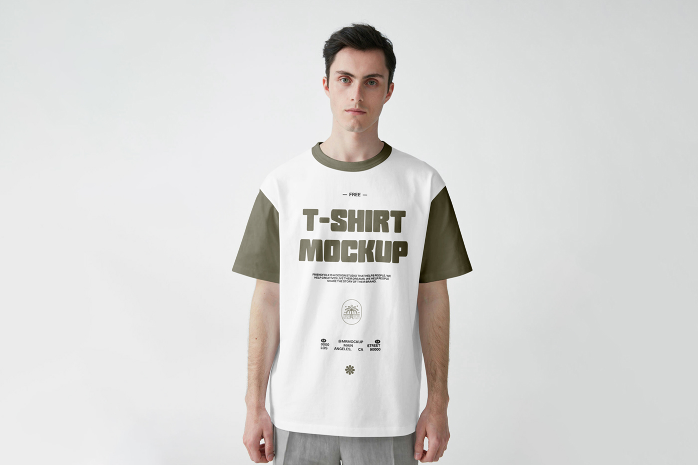 Standing men wearing t-shirt with a green logo in front of the white wall.