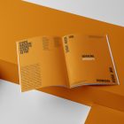 Open a4 magazine with orange playful design on orange cube from studio magazine mockups.