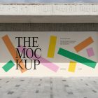 Front view, rectangle with colorful graphics and black typography space built into a stone beige wall from storefront mockups product.