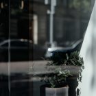 Front view, at an angle of 45 degrees, transparent glass window from storefront mockups product where you can see the reflection of city life.
