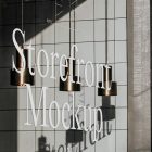 Front view, at an angle of 45 degrees, clean glass window with colorful graphics and white typography with visible shadows from storefront mockups product.