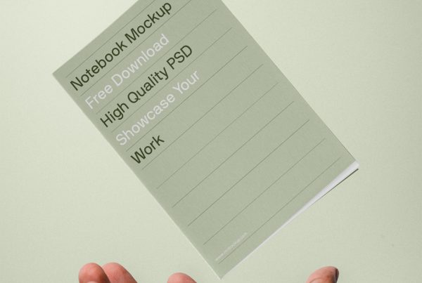 Front view, small notebook mockup levitating over men hand in front of the green wall.