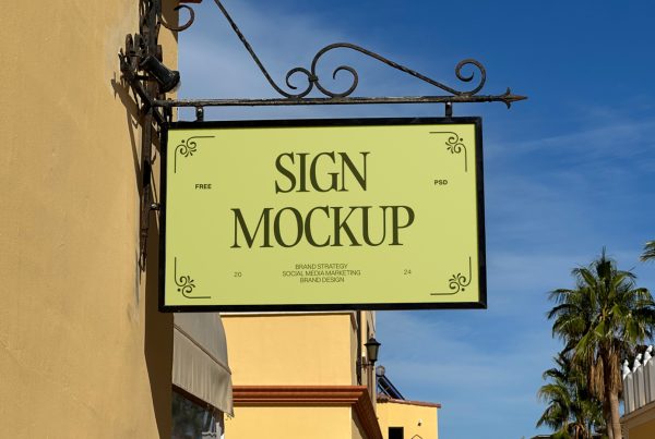 Front view, vintage sign mockup with black metal frame hanging in front of the buildings.