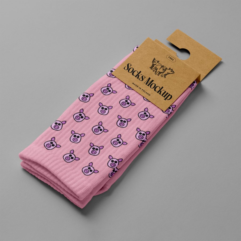 View from above, pink pair of socks mockup with a craft paper label attached to it, laying on the gray floor.